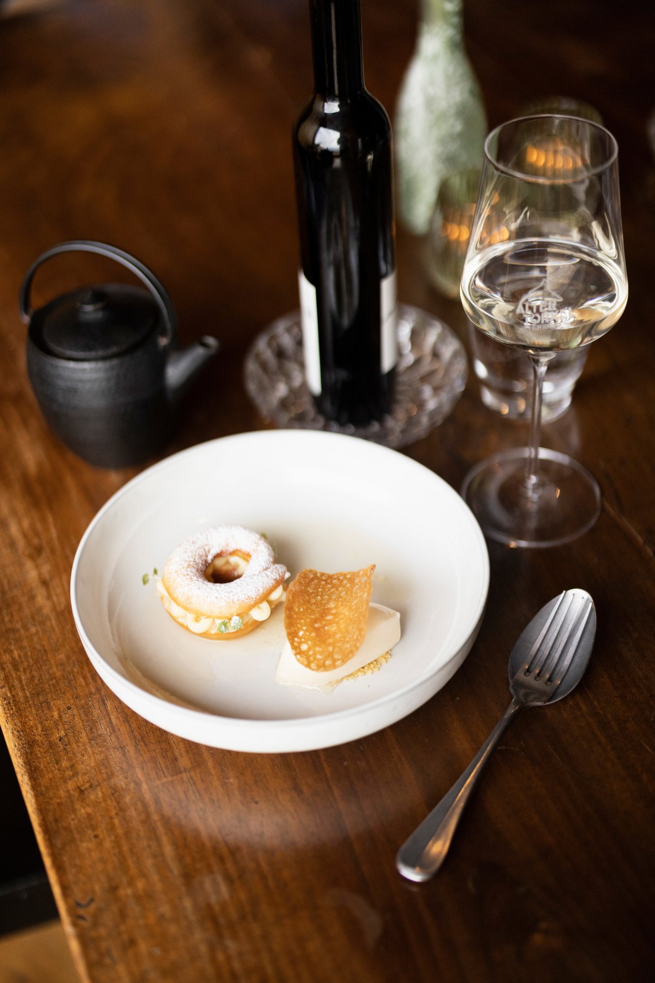 weisser desserteller mit spitzbube und konfekt  und weissweinglas vom alten torkel mit 