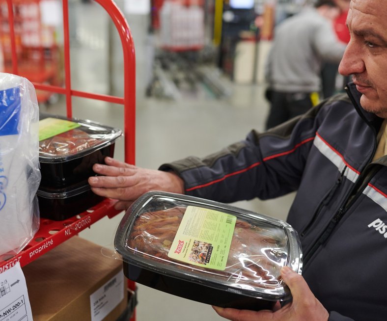 Pistor Mitarbeitender Besim Zeqiri verdichtet die Produkte auf dem roten Rollbehälter